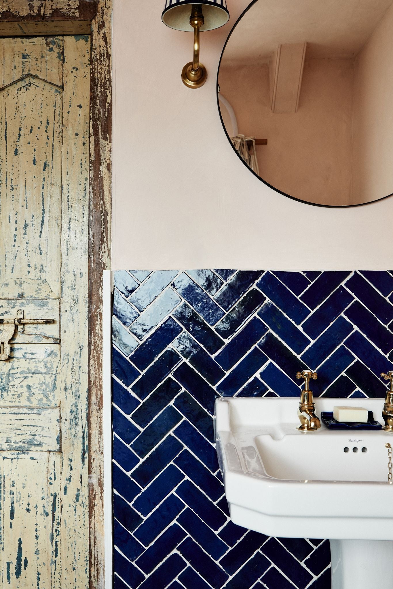Blue Zillege Tiles in a herringbone pattern behind a ceramic washstand in a rustic bathroom 