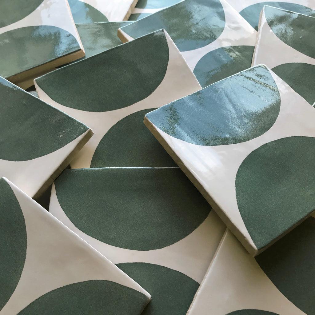 A selection of green hand painted tiles with spot design