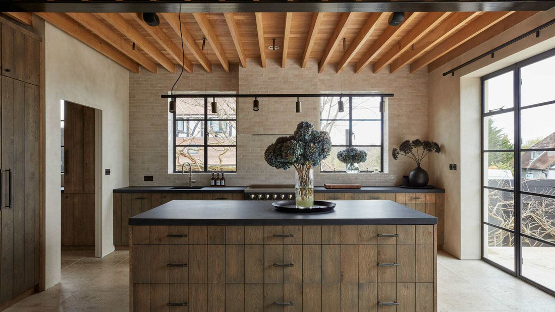 A wooden kitchen island in a contemporary style kitchen with wooden beams and bespoke kitchen joinery.