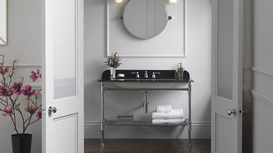 Black marble freestanding washstand in a stylish bathroom with round mirror and wall lights either side