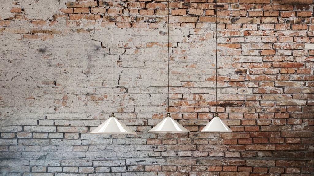 3 glass coolie pendant lights in a line against an exposed brick wall