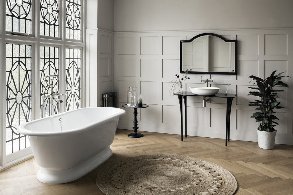 Freestanding bathtub in a stylish bathroom with freestanding washstand and indoor plats
